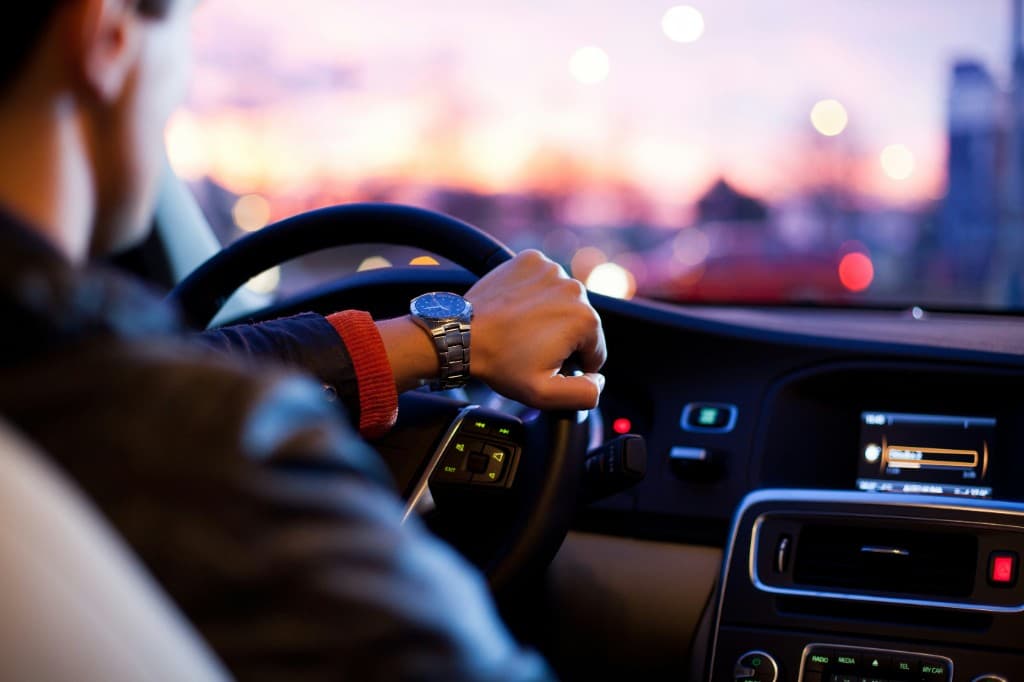 Driver behind the wheel of a modern car at sunset